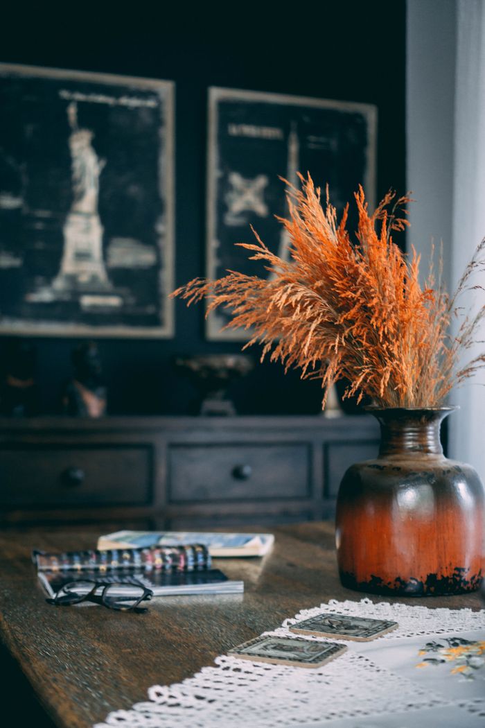 about-img-01 Warm and inviting autumn setting with a rustic vase filled with wheat, cozy decorations, and books.